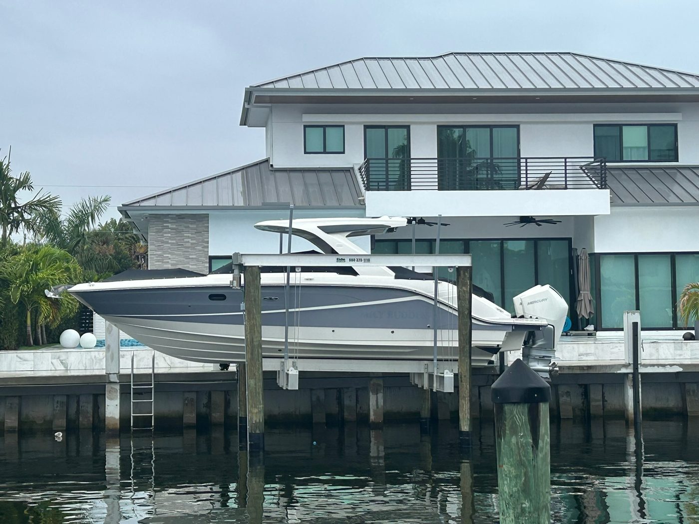 Cruiser on properly-sized aluminum boat lift at modern Boca Raton waterfront home